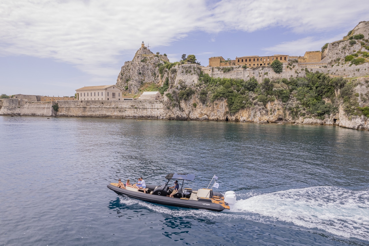 Golden sunset light illuminating a private boat cruising along the Corfu coastline