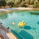 Calm shallow turquoise cove in Corfu with float and beach ball, ideal for a family boat day